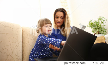 Cute little girl on couch with mom use laptop Cute little girl on couch with mom use laptop 114601209
