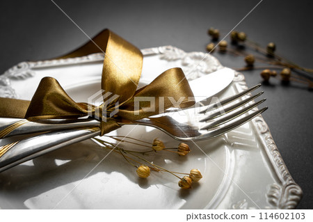 Romantic tabble setting with ribbon, plates, cutlery on black background. Empty plate. Mockup design layout for your text. Love romantic concept. Copy space. Top view. Flat lay. Romantic tabble setting with ribbon, plates, cutlery on black background. Empty plate. Mockup design layout for your text. Love romantic concept. Copy space. Top view. Flat lay. 114602103