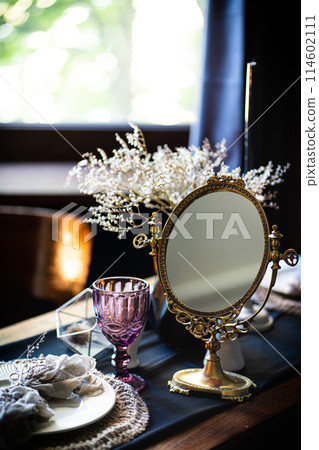 Retro vintage table. Arrangement on the table, antique mirror, plates, vintage mug. Ancient mirror on the table 114602111