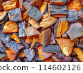 close-up image of a pile of chopped firewood. warm tones and visible grain and rings indicate the wood is ready for use as fuel. 114602126