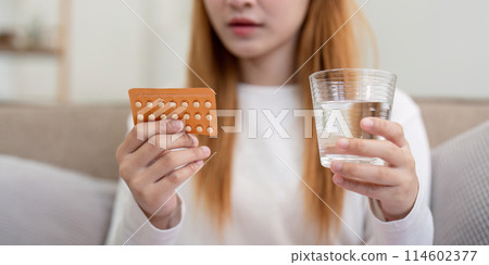 Woman holding birth control pills and a glass of water at home. Concept of health, contraception, and women's healthcare 114602377