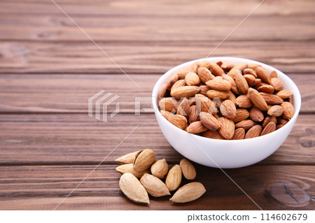 White bowl of almonds on brown wooden background 114602679