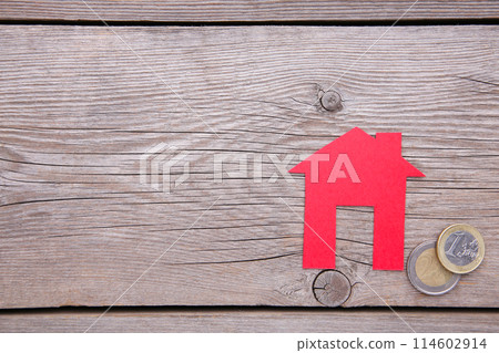Red paper house with red roof, with coins on grey background 114602914