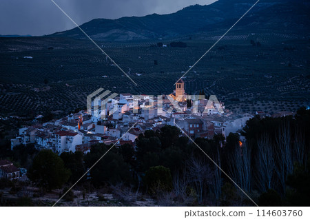 View from the hill of medieval historical urban village of Quesada in the province of Jaen, at dawn with the illuminated bell tower and while houses. Beauty in Spain nature. Travel and tourism concept 114603760