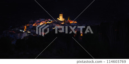 View from the hill of medieval historical city of Quesada in province of Jaen, with illuminated bell tower and while houses in the night time. Andalusia. Spain. Beauty in nature. Travel and tourism 114603769
