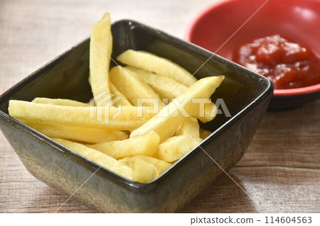 French fries mixed with salt in cup dipping ketchup on table   114604563