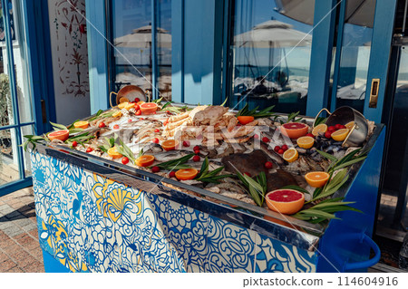 sea food on outside store counter. Fish and crab on ice decorated with fresh citrus fuit 114604916