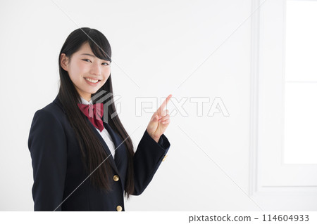一個微笑的高中女孩在易於使用的白色背景上直視相機，透過指向右側的空間來進行建議的姿勢。 114604933