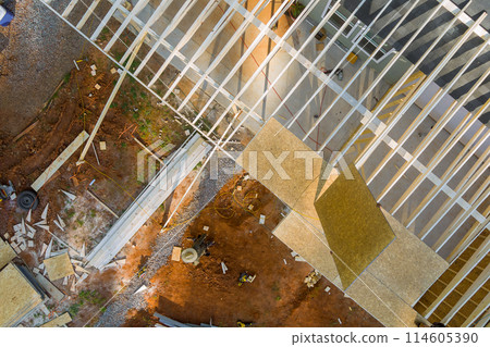 During construction project, carpenter hammers nail into an OSB plywood panel on roof During construction project, carpenter hammers nail into an OSB plywood panel on roof 114605390