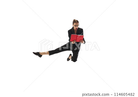 Emotional businesswoman in motion, in mid-air pose jumping with shocked face and looking in book, notes isolated on white background 114605482