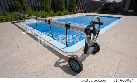 Home outdoor pool covered with film to save chemicals, water and heat preservation 114606034