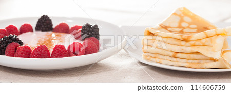 Breakfast of raspberries and blackberries with yogurt and pancakes on table 114606759