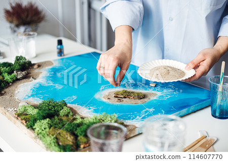 Artist Applying Final Touches to a 3D Epoxy Resin Coastal Artwork Artist Applying Final Touches to a 3D Epoxy Resin Coastal Artwork 114607770