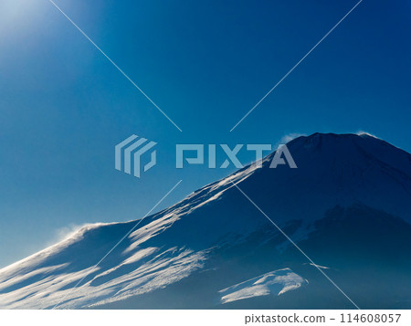 Mount Fuji in early spring: Snow and smoke blowing across the mountainside in strong winds 114608057