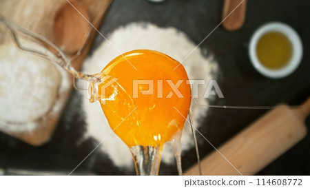 close up view of yolk falling on flour on black stone table close up view of yolk falling on flour on black stone table 114608772