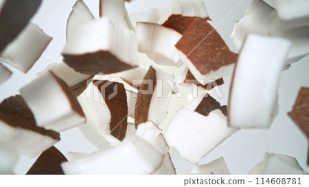 Fresh coconut pieces falling into cream, top down view 114608781