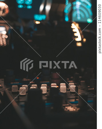 Cockpit view of an airplane during a night-time flight with illuminated instrument panels 114609030