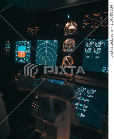 Cockpit view of an airplane during a night-time flight with illuminated instrument panels Cockpit view of an airplane during a night-time flight with illuminated instrument panels 114609034