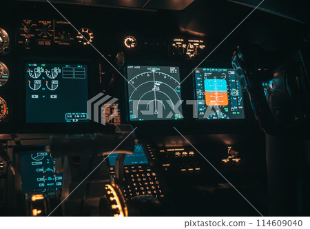 Cockpit view of an airplane during a night-time flight with illuminated instrument panels 114609040