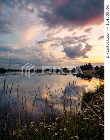 Calm river at sunset with reflective sky in rural countryside landscape Calm river at sunset with reflective sky in rural countryside landscape 114609050