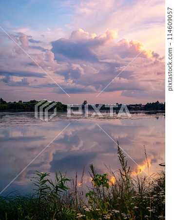 Calm river at sunset with reflective sky in rural countryside landscape Calm river at sunset with reflective sky in rural countryside landscape 114609057