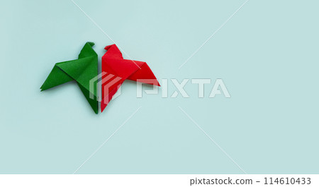 banner two doves made of origami paper in red and green colors facing each other on pastel blue background 114610433