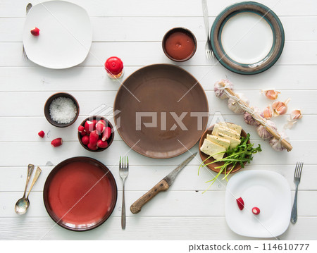 table served for four with empty plates, radish and garlic 114610777
