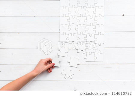 hand holding a piece of white uncompleted puzzle hand holding a piece of white uncompleted puzzle 114610782