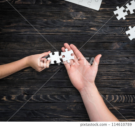 pieces of white puzzle in hands pieces of white puzzle in hands 114610789