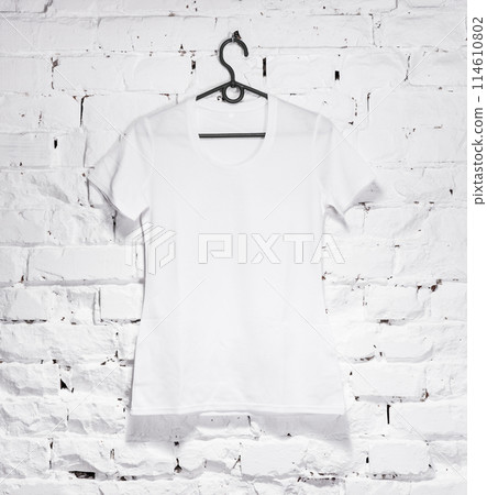 brick whitewashed wall with white shirt on hanger 114610802