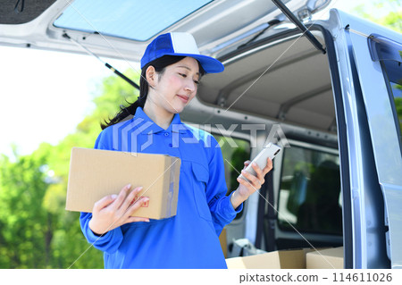 Delivery driver woman holding luggage and looking at smartphone 114611026