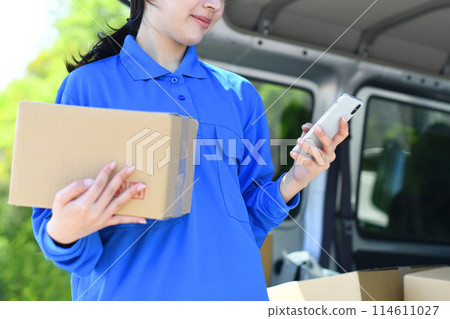 Delivery driver woman holding luggage and looking at smartphone Delivery driver woman holding luggage and looking at smartphone 114611027