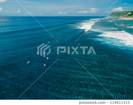 Aerial drone view with surfers on surf spot. Perfect waves with surfers in clear ocean 114611315