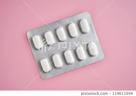 Open pack of pills on a pink background. 114611894