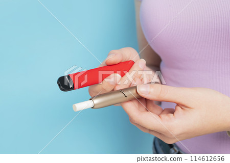 Disposable electronic cigarette and iqos in hand close up. 114612656