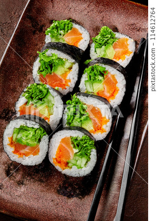 Futomaki rolls with salmon, tobiko and greens on rustic plate Futomaki rolls with salmon, tobiko and greens on rustic plate 114612764