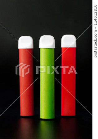 Colorful disposable electronic cigarettes on a black background. The concept of modern smoking, vaping and nicotine. Colorful disposable electronic cigarettes on a black background. The concept of modern smoking, vaping and nicotine. 114612816
