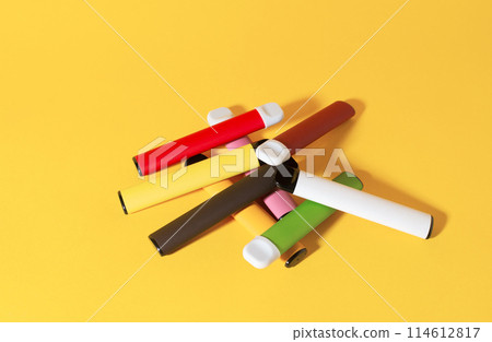 Layout of colorful disposable electronic cigarettes with shadows on a yellow background. The concept of modern smoking, vaping and nicotine. Top view 114612817