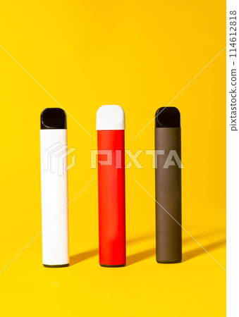 Colorful disposable electronic cigarettes with shadows on a yellow background. The concept of modern smoking, vaping and nicotine. 114612818
