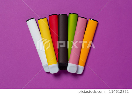 Set of colorful disposable electronic cigarettes on a purple background. The concept of modern smoking, vaping and nicotine. Top view 114612821