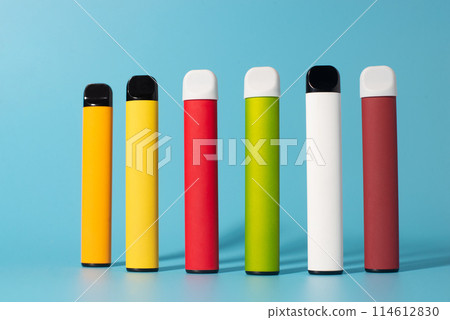 Set of colorful disposable electronic cigarettes with shadows on a blue background. The concept of modern smoking, vaping and nicotine. Top view 114612830