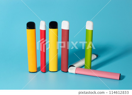 Set of colorful disposable electronic cigarettes with shadows on a blue background. The concept of modern smoking, vaping and nicotine. Top view 114612833
