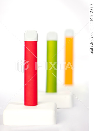 Set of colorful disposable electronic cigarettes on a display stand on a white background. The concept of modern smoking, vaping and nicotine. 114612839