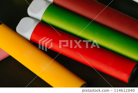 Colorful disposable electronic cigarettes on a black background. The concept of smoking, vaping and nicotine. Colorful disposable electronic cigarettes on a black background. The concept of smoking, vaping and nicotine. 114612840
