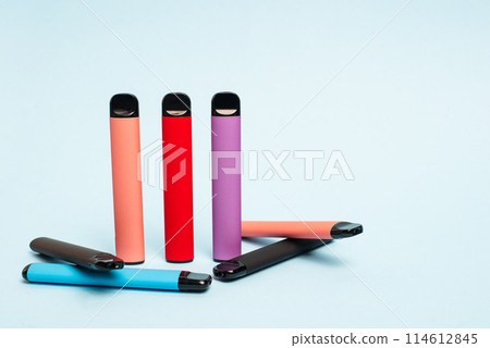 Layout of colorful disposable electronic cigarettes on a light blue background. The concept of modern smoking, vaping and nicotine. 114612845
