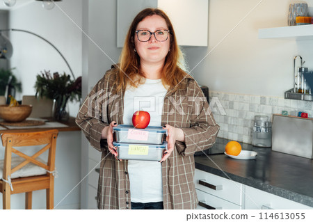 Healthy diet plan for weight loss, daily ready meal menu. Plus size young Woman holding lunch boxes just cooked in advance, ready to be served. Containers with eco healthy food. Pre-cooking concept. Healthy diet plan for weight loss, daily ready meal menu. Plus size young Woman holding lunch boxes just cooked in advance, ready to be served. Containers with eco healthy food. Pre-cooking concept. 114613055