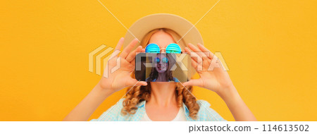 close up of modern happy young woman taking selfie with smartphone on yellow background close up of modern happy young woman taking selfie with smartphone on yellow background 114613502