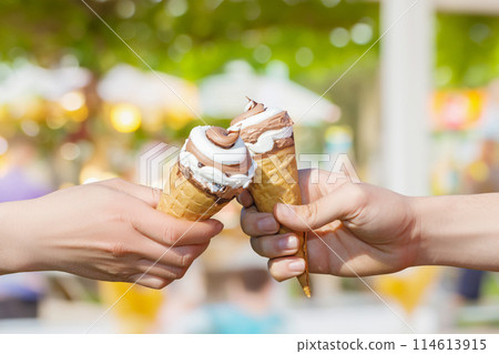 Two hands holding ice cream cone . 114613915