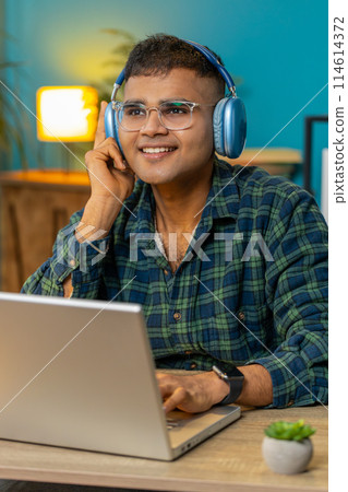 Business man listening music through wireless headphones relaxing taking a break laptop on table Business man listening music through wireless headphones relaxing taking a break laptop on table 114614372