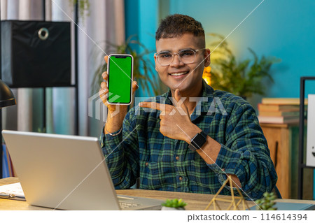 Indian business man holds smartphone with green screen chroma key mock up recommend good application 114614394